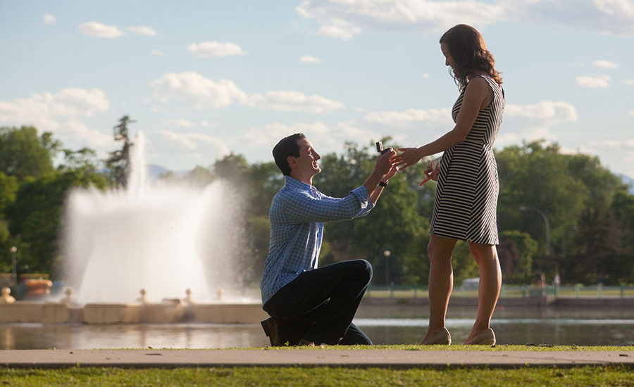 Man proposing on one knee with fountain in background