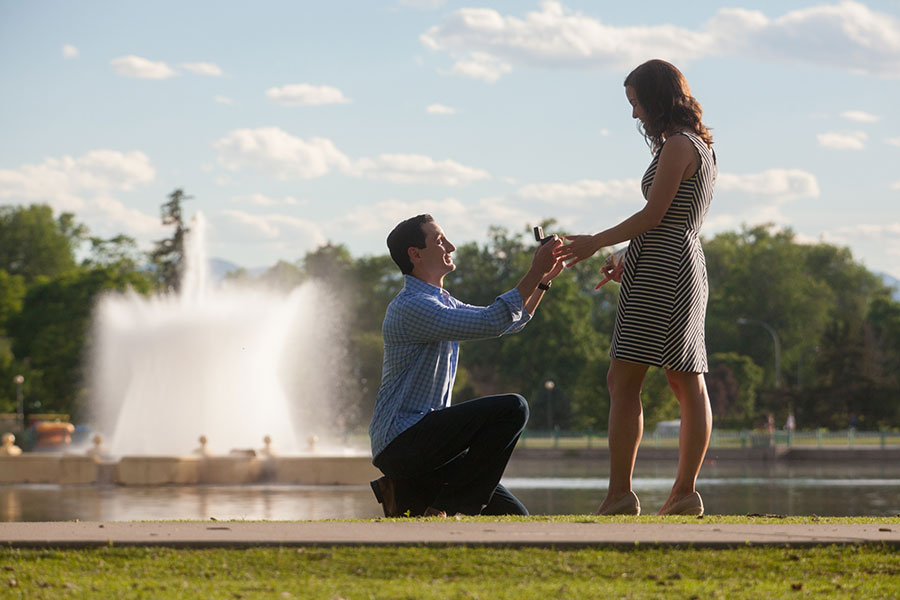 Man proposing on one knee with fountain in background