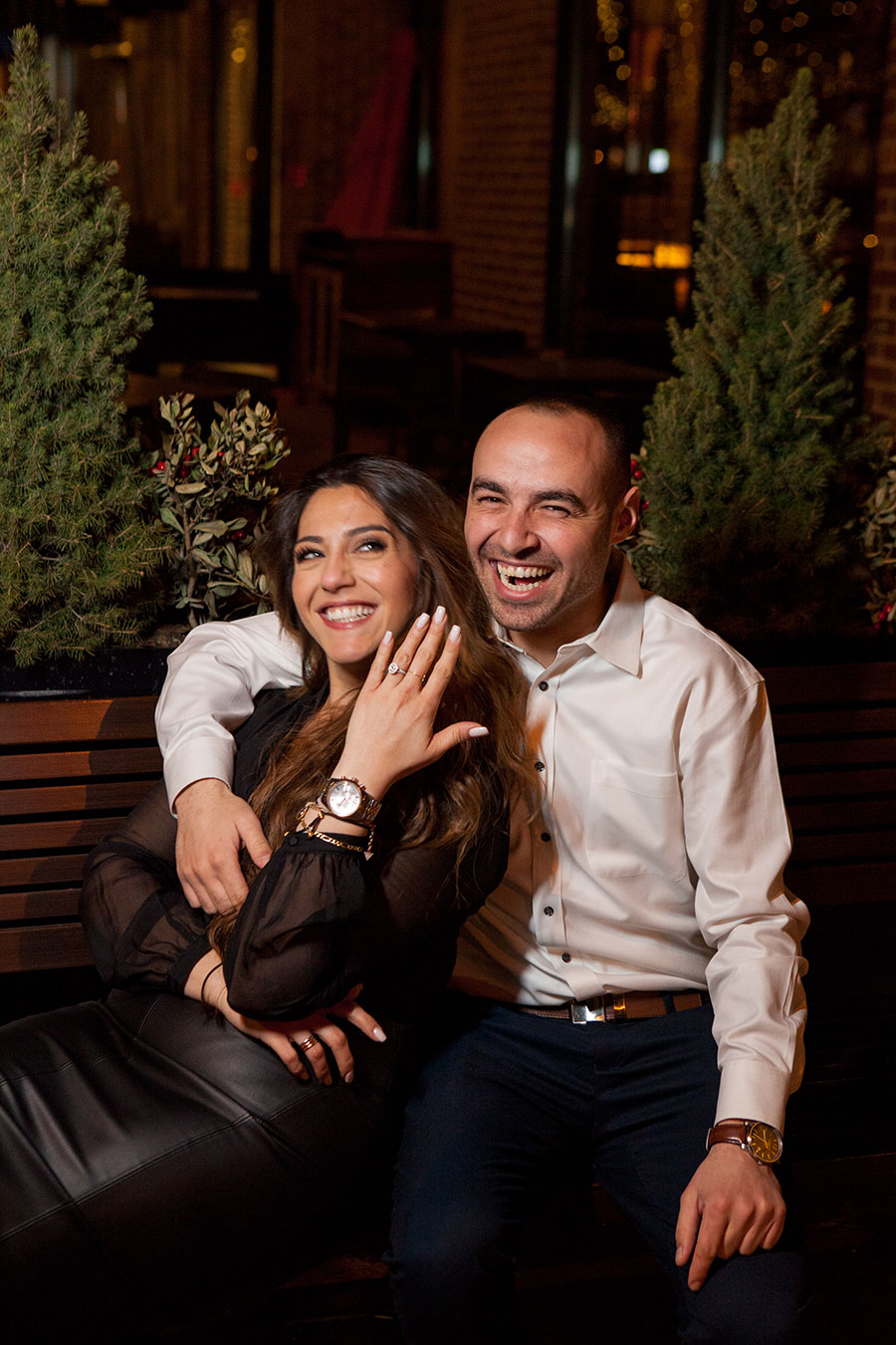 couple laughing at camera holding up hand with ring